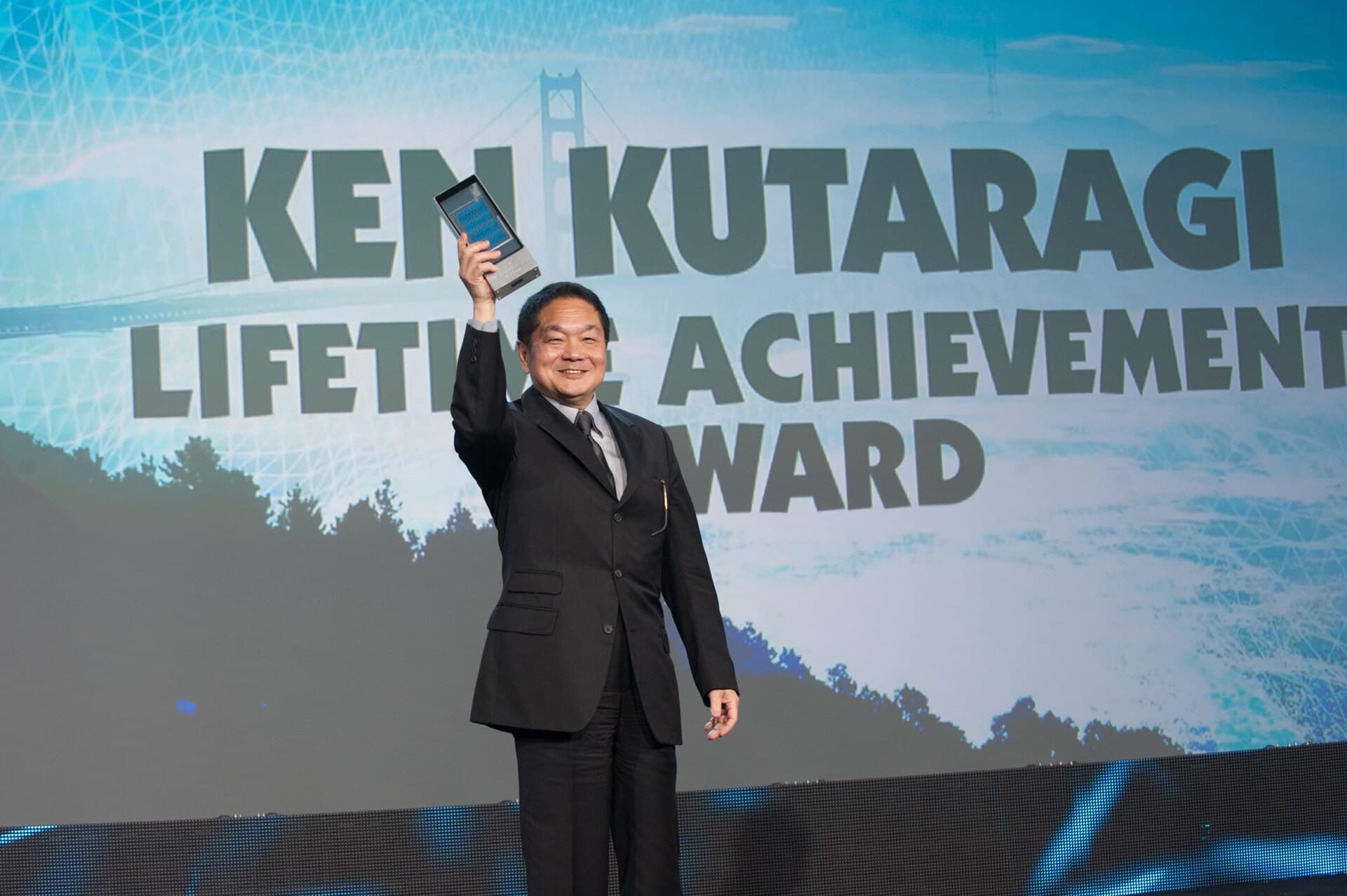 Ken Kutaragi, criador do PlayStation, ergue o troféu de Lifetime Achievement no palco do Game Developers Choice Awards de 2014