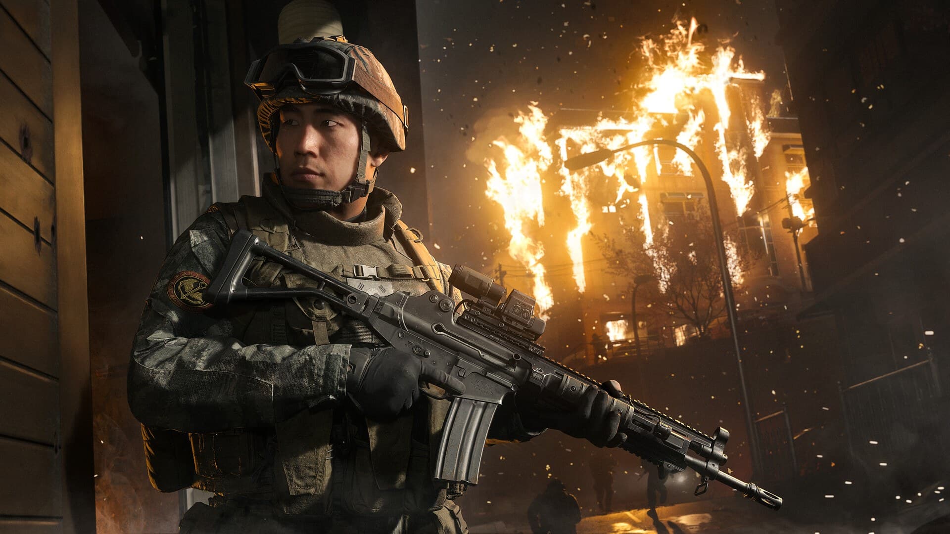 Operador de Modern Warfare 4 com fuzil diante de um prédio em chamas, em imagem oficial do lançamento