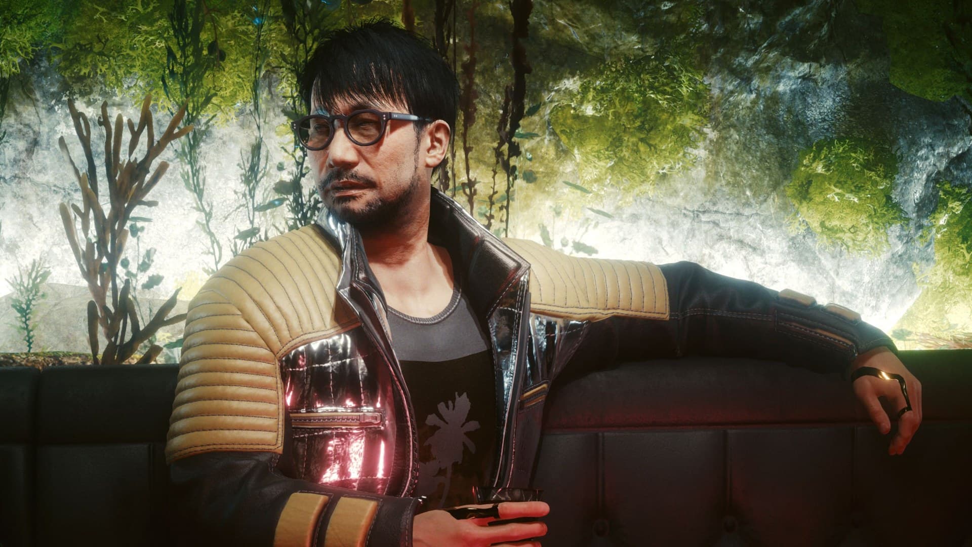 Hideo Kojima como Hideyoshi Oshima, sentado num sofá do Konpeki Plaza em Cyberpunk 2077