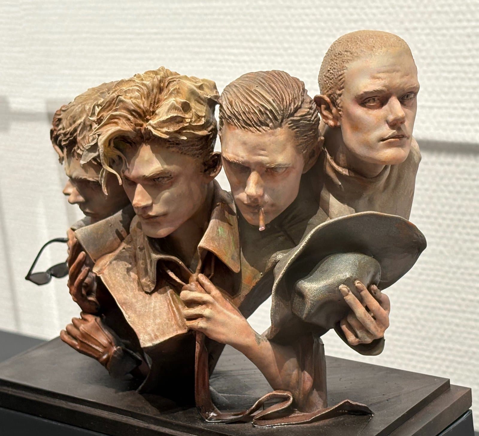 Detalhe da escultura: um Skarsgård afrouxa a gravata, outro fuma e outro tira o chapéu.